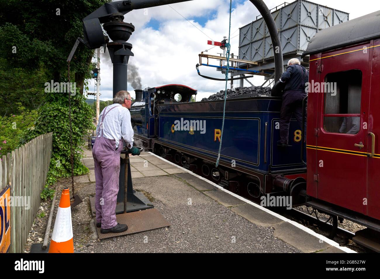 steam railway. Railway station. volunteer staff refill the water tanks.  (water tank and train filling hose bowser). Boat of Garten Scotland UK  Stock Photo - Alamy