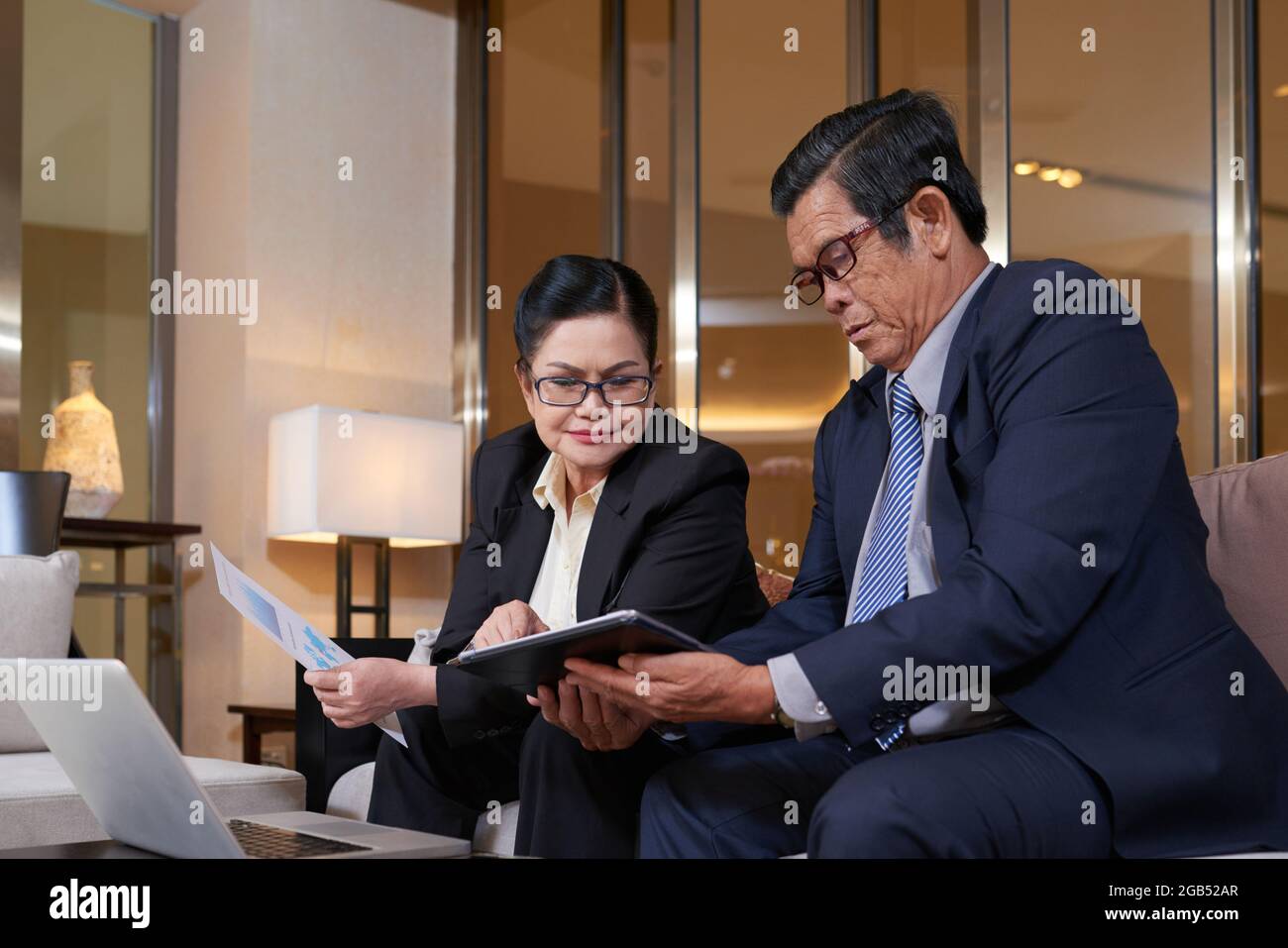 Senior company CEO showing tablet computer with annual report on screen ...