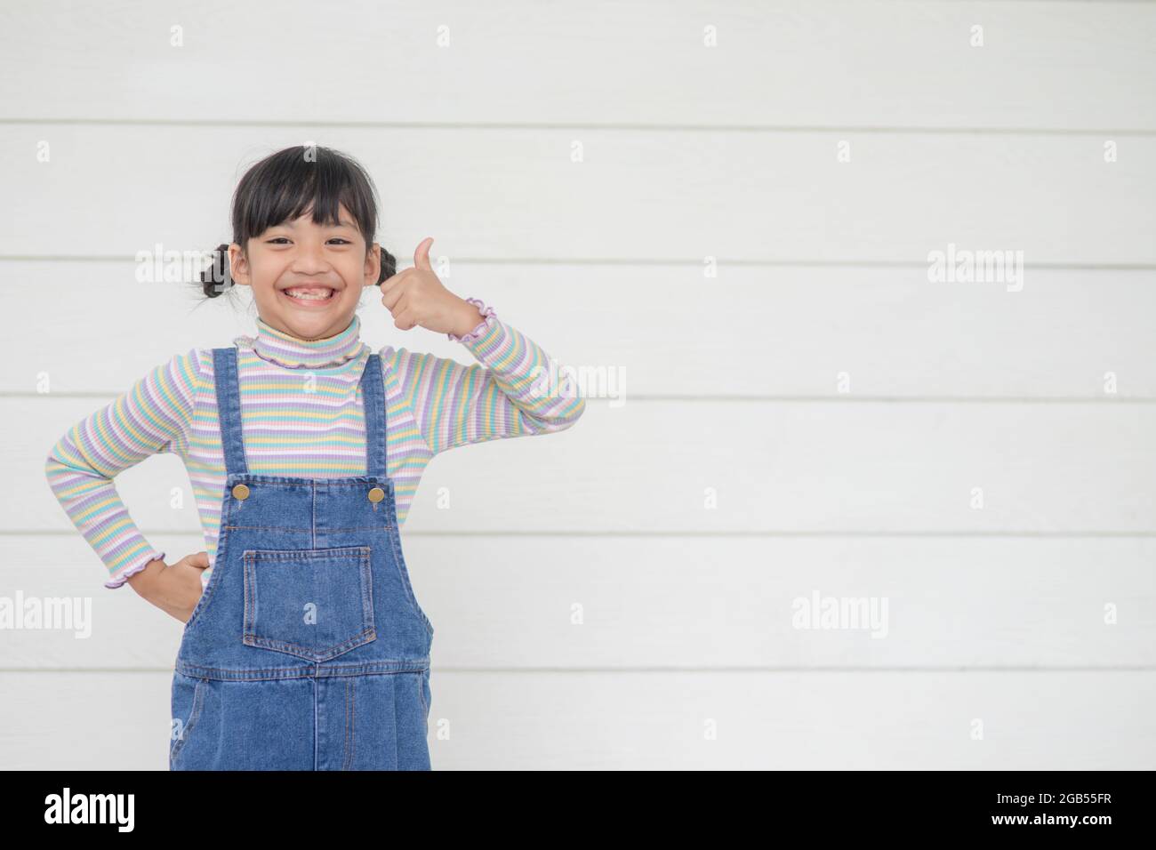 Portrait of little cute Asian girl with her thump up, advertisement concept, little Asian teenage thumps up with the white background and space Stock Photo