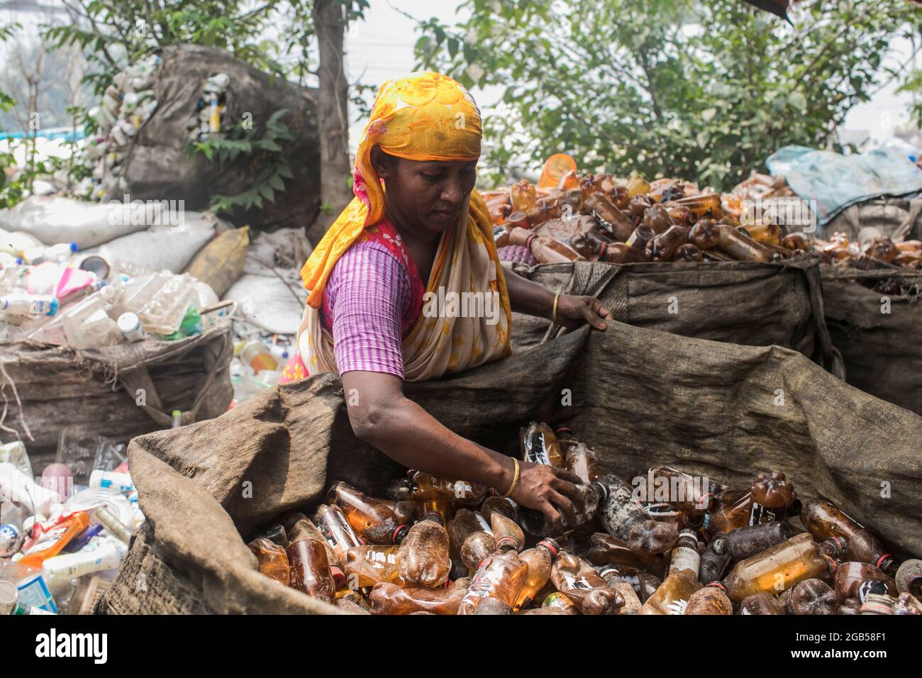 A Bangladeshi woman works in a plastic bottle recycling factory besides