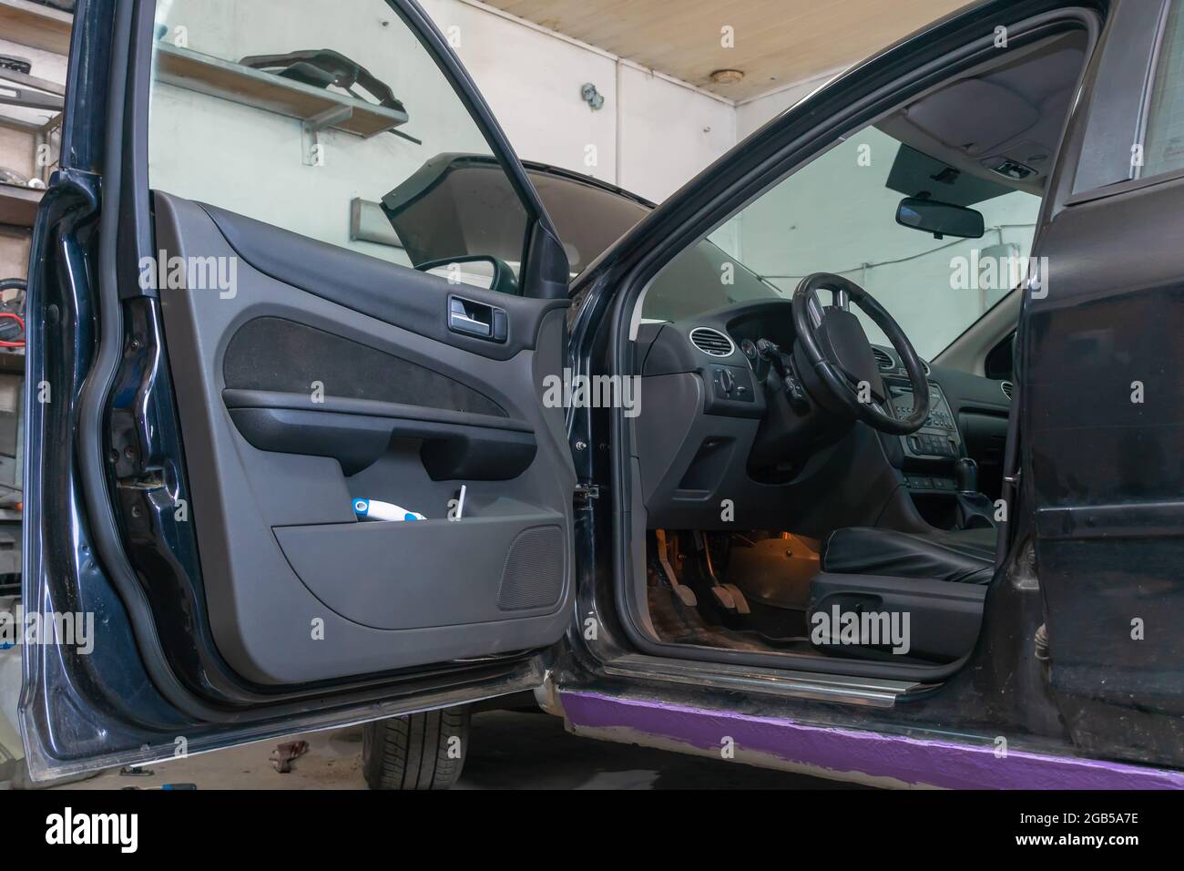 Master restores an old retro car in the garage. He removes the doors or