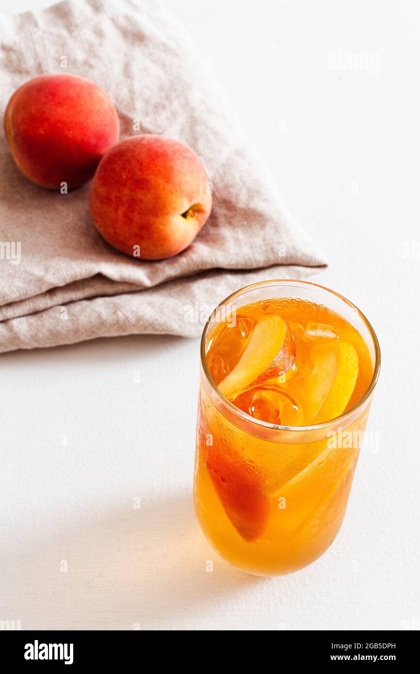 https://c8.alamy.com/comp/2GB5DPH/glass-of-homemade-cold-brew-peach-iced-tea-with-fresh-peaches-on-linen-in-the-background-2GB5DPH.jpg