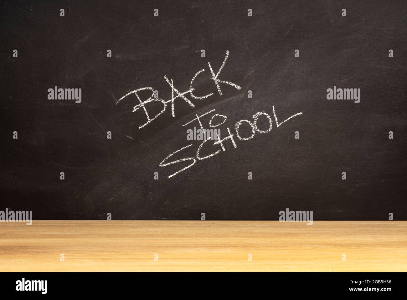 Blackboard with handwritten Back To School phrase and wooden table Stock Photo