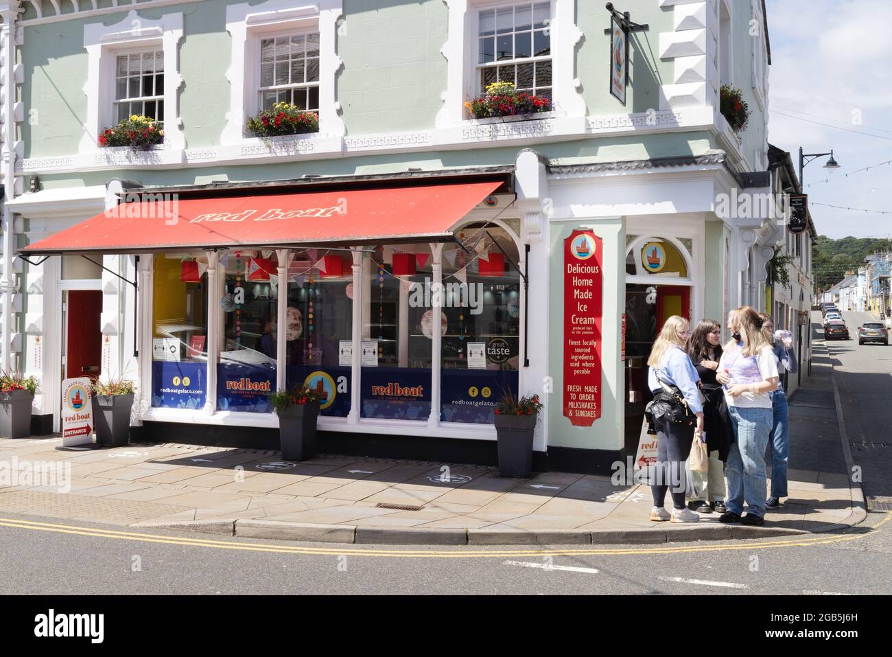 People outside the popular Red Boat ice cream shop, the High street, town centre, Beaumaris Anglesey Wales UK Stock Photo