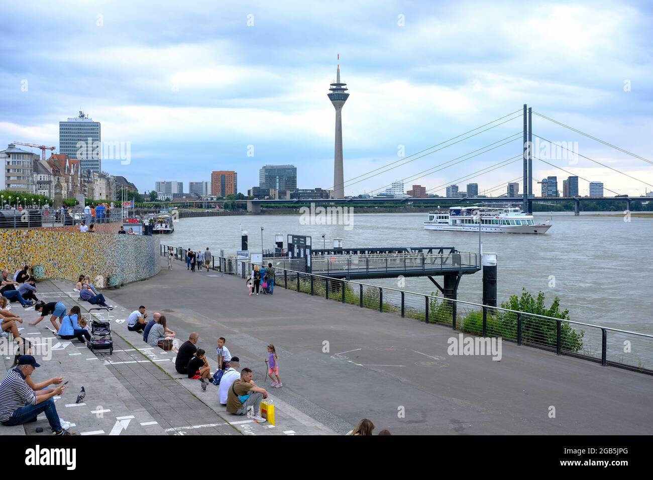 30.07.2021, Duesseldorf, Nordrhein-Westfalen, Deutschland - Menschen sitzen an einem bewoelkten Julitag auf der Freitreppe zwischen Burgplatz und Ufer Stock Photo
