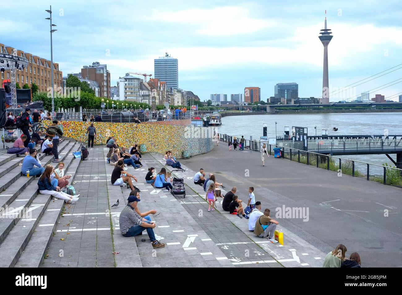 30.07.2021, Duesseldorf, Nordrhein-Westfalen, Deutschland - Menschen sitzen an einem bewoelkten Julitag auf der Freitreppe zwischen Burgplatz und Ufer Stock Photo