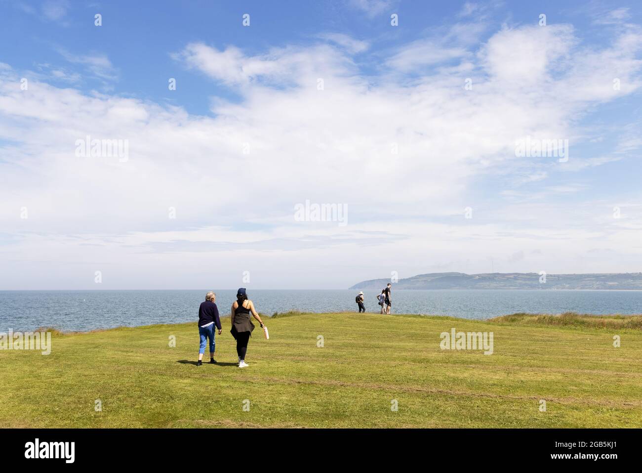 People walking the Wales Coast path, at Red Wharf Bay on the Isle of Anglesey Coastal path in summer, Anglesey, Wales UK Stock Photo