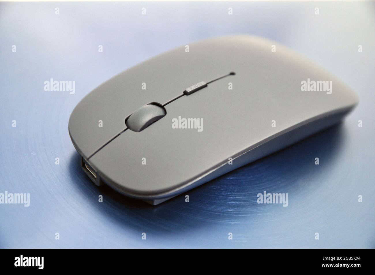 Wireless rechargeable computer mouse on a blue background. Technology Stock Photo