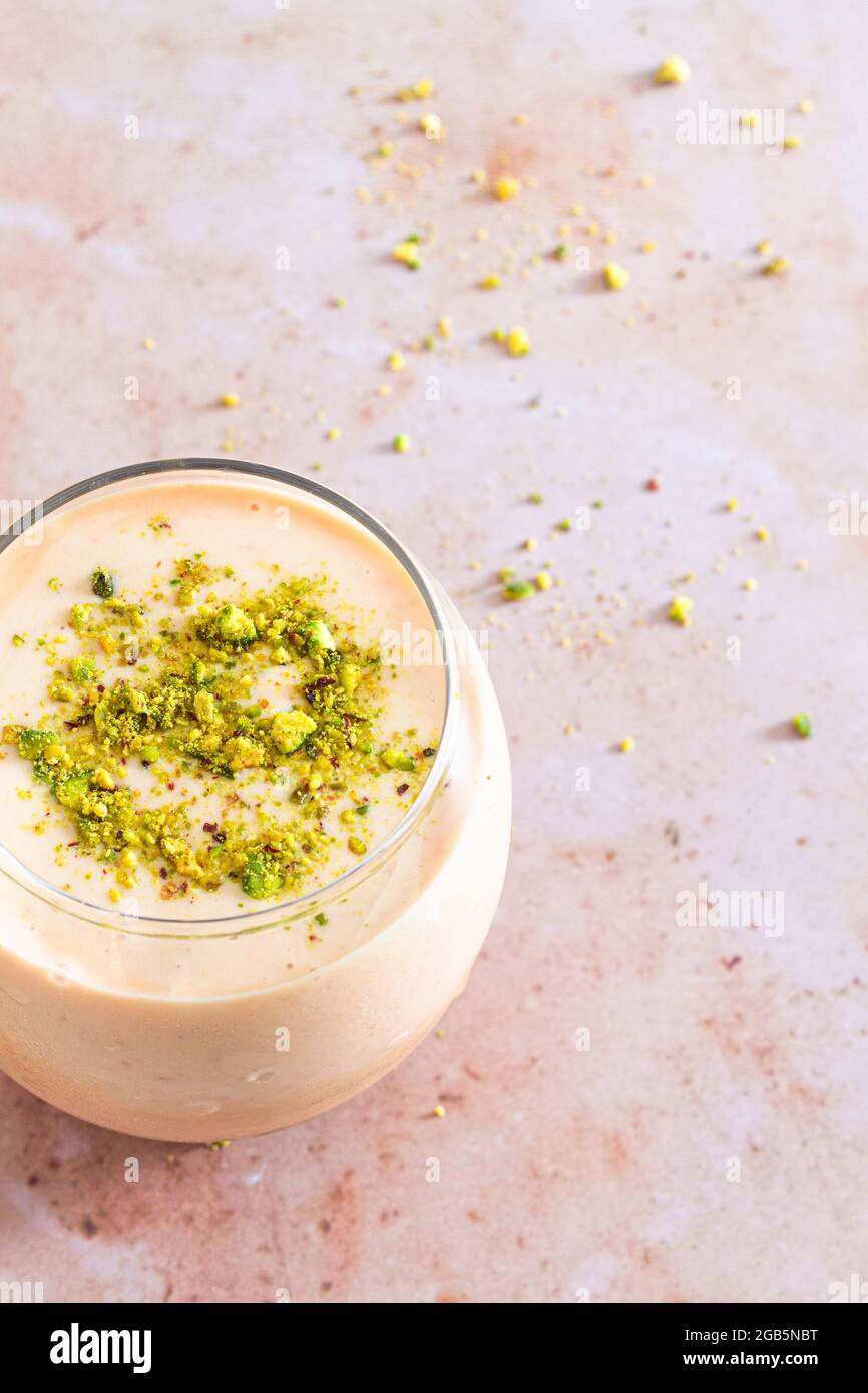 Glass of fresh homemade apricot smoothie topped with chopped pistachio. Stock Photo