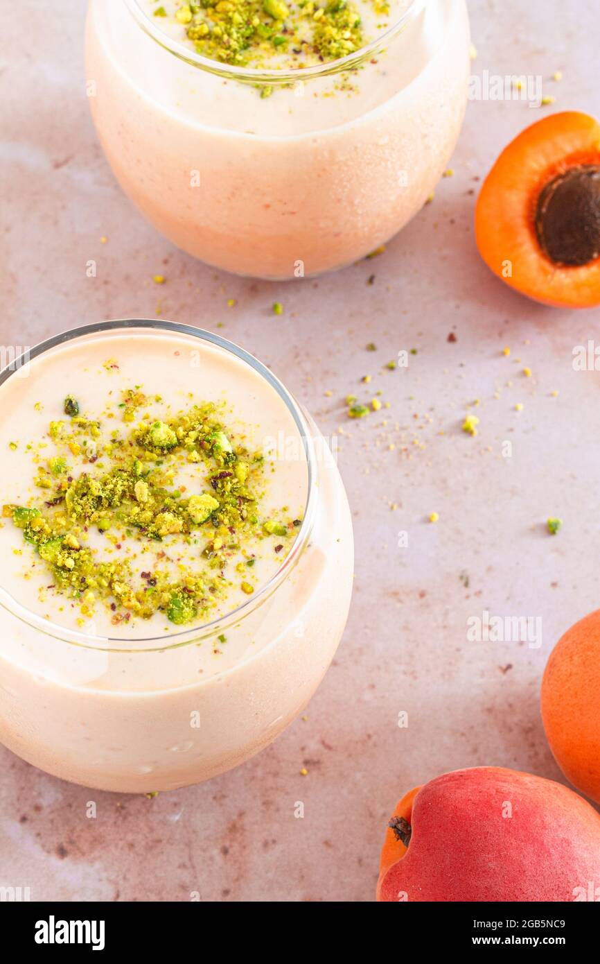 Two glasses of fresh homemade apricot smoothie topped with chopped pistachio nut. Stock Photo