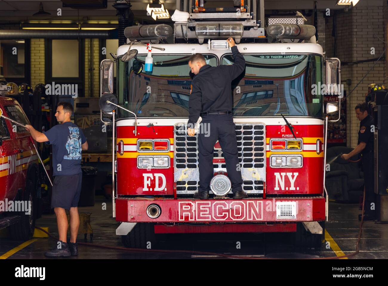 Firefighters wash the Fire trucks at garage of FDNY Ladder 3 NYC. Stock Photo