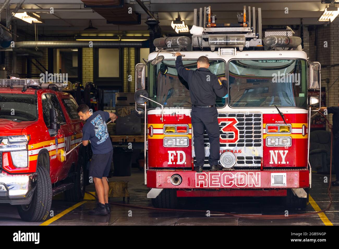 Firefighters wash the Fire trucks at garage of FDNY Ladder 3 NYC. Stock Photo