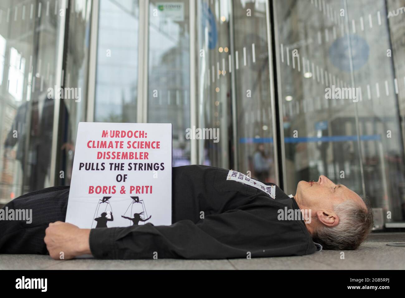 London, UK. August 2nd 2021: Reverend Tim Hewes, aged 71, sewed his lips shut outside News UK offices at lunchtime today. His action was to draw attention to the silencing of climate science by Rupert Murdoch and News Corp, which has led to a catastrophic lack of effective action to tackle the climate crisis. He held placards reading “Murdoch did this, muted climate science”, “Murdoch to the dock for ecocide”, “The Murdoch legacy? The 6th Mass Extinction on planet earth”. London, UK. Credit: Joshua Windsor/Alamy Live News Stock Photo