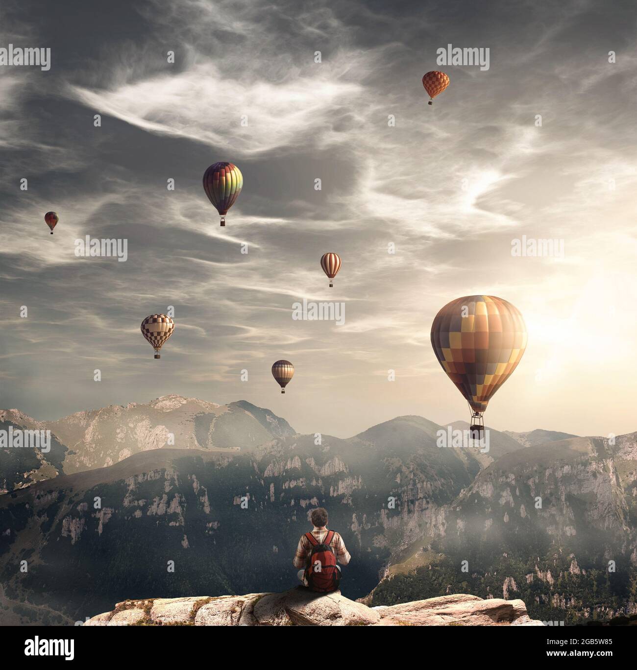 Hiker on top of a mountain peak admiring the hot air balloons flying.Enjoy the moment. Stock Photo