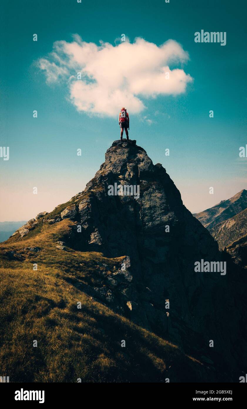 Hiker on top of a mountain hill with a cloud above. Stock Photo