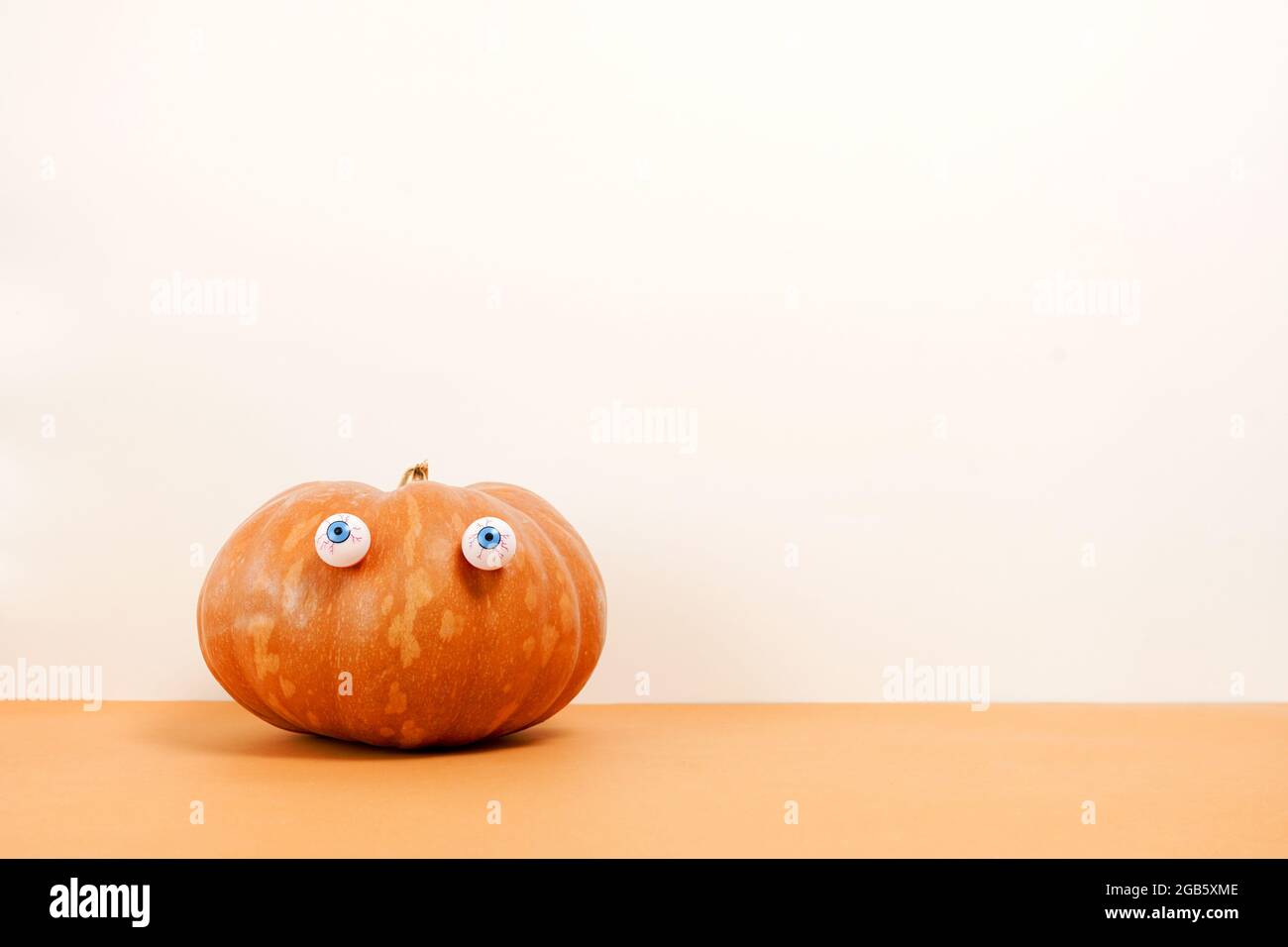 Halloween pumpkin with eyes on white and orange background. Cute halloween pumpkin . copyspace Stock Photo