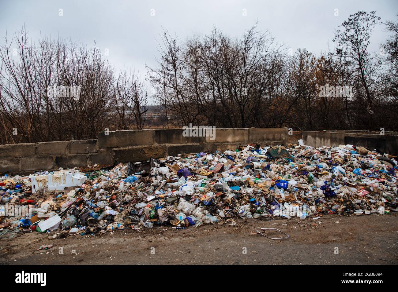 Dneprorudnoe, Ukraine - January 29 2020:Garbage dump on the grass near the forest. Ecological disaster. Illegal dump. Pollution of nature. Stock Photo