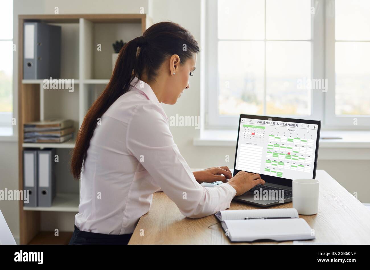 Woman organizing her work schedule using Calendar and Planner on laptop computer Stock Photo