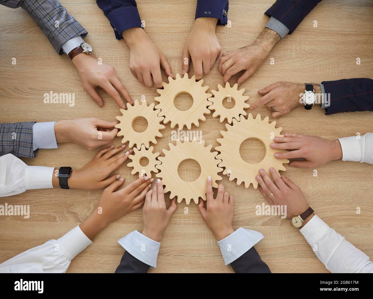 Team of people join cogwheels as metaphor for teamwork and effective business system Stock Photo