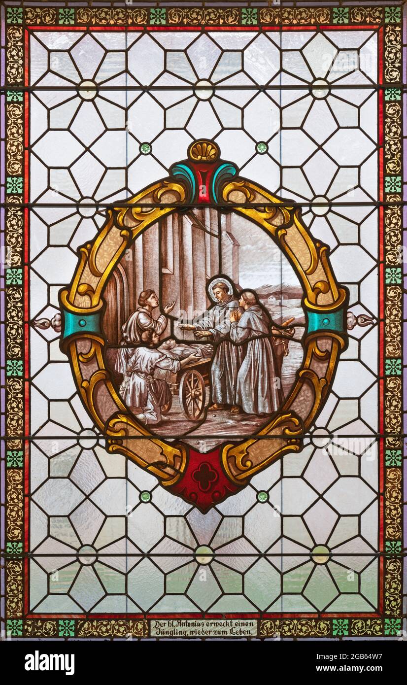 VIENNA, AUSTIRA - JUNI 17, 2021: The Saint Anthony of Padua reviving a Dead Man on the stained glass of church  Alserkirche  by Franz Gotzer Stock Photo