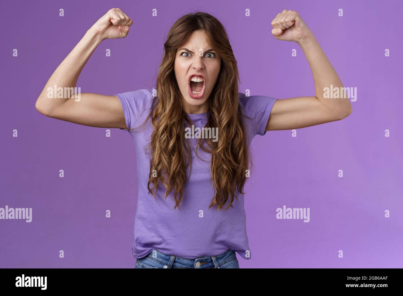 Funny curlyhaired girl raising hands fist pump show muscles yelling