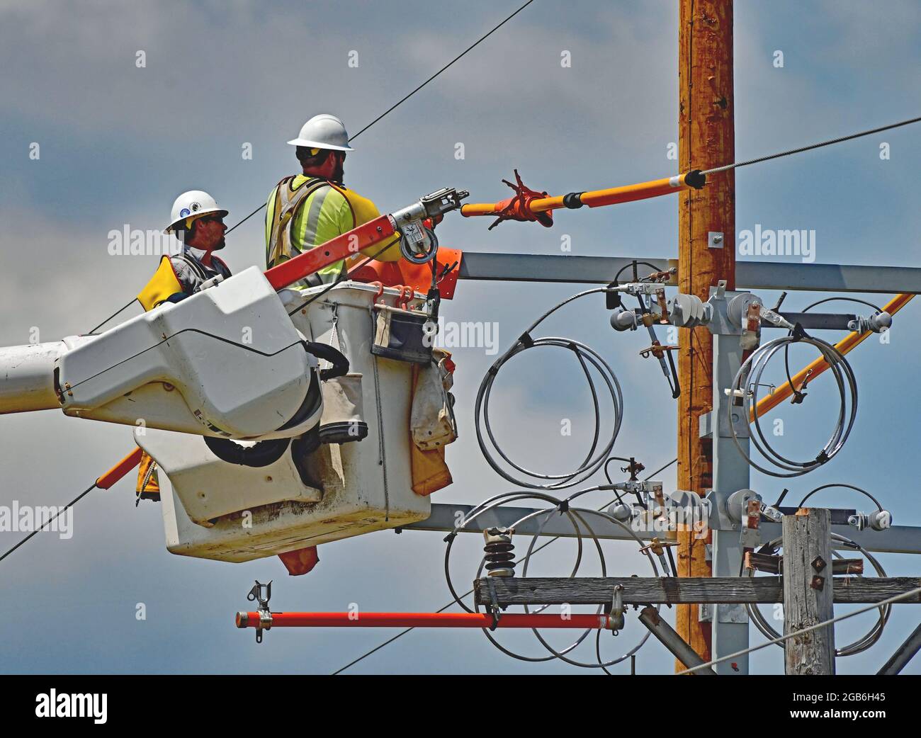 As part of improving the infrastructure of the local electrical grid a work  crew from Every electric power utility using full safety gear place covers  over the high tension wires to protect