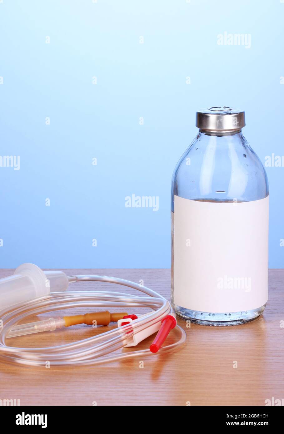 Bottle of intravenous antibiotics and plastic infusion set on wooden