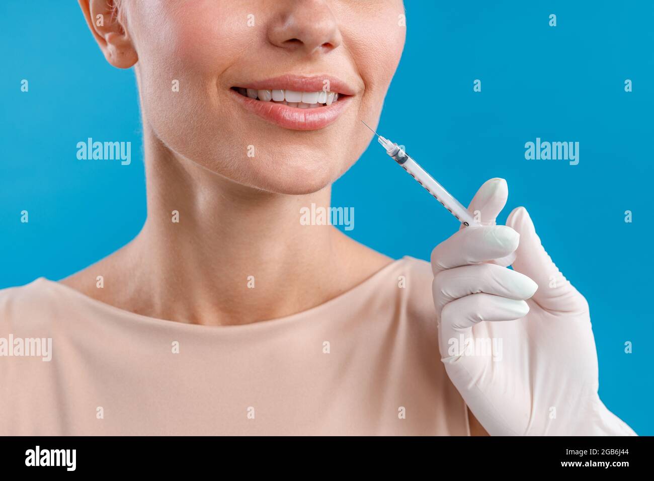 Close up shot of smiling woman receiving botox injection in lips from beautician Stock Photo