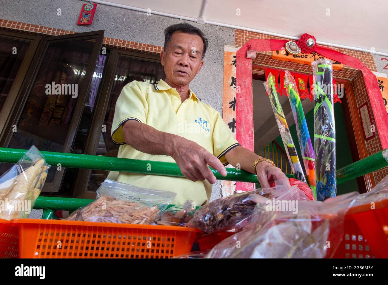A shop keeper in a village in China sorts his wares ready for sale Stock Photo