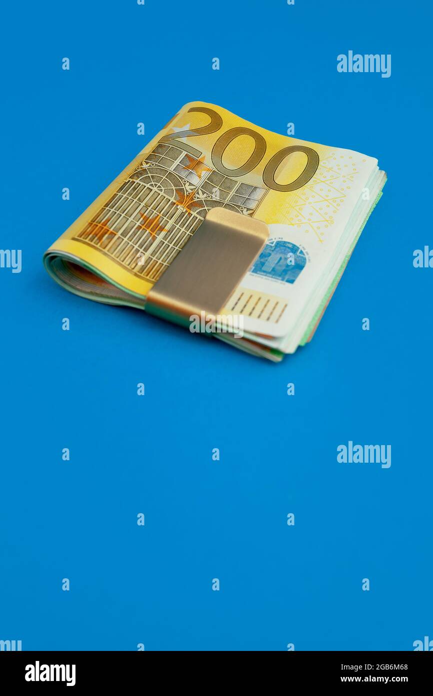 Money clip with euro bills on blue background Stock Photo - Alamy