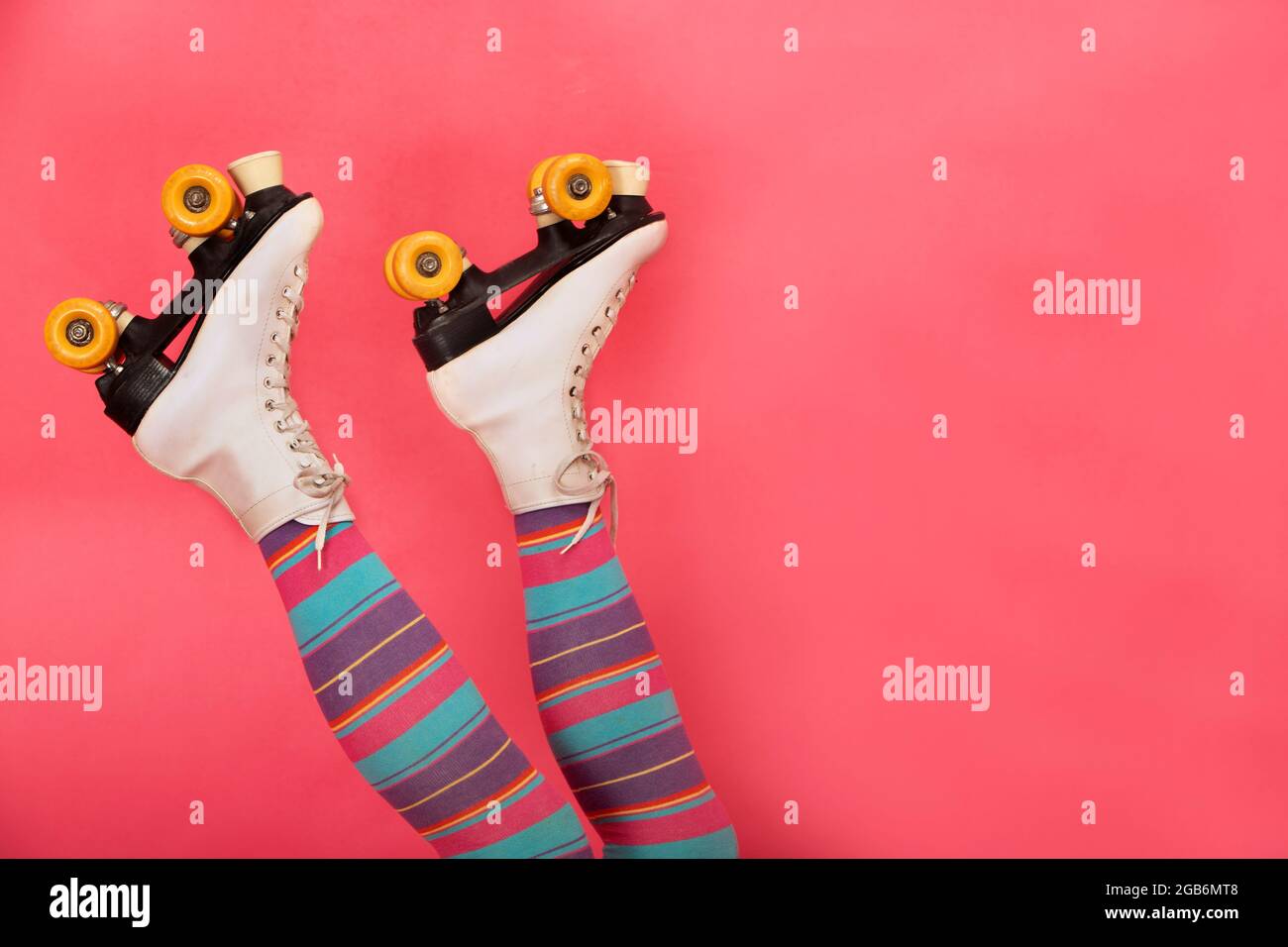 legs upside down with color stockings and retro skates on a pink background Stock Photo