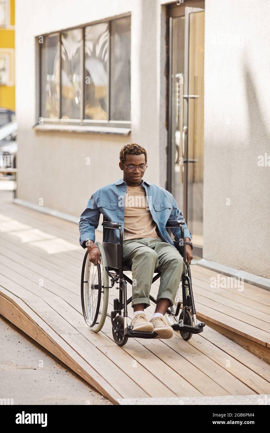 Disabled young AfricanAmerican man using manual wheelchair while