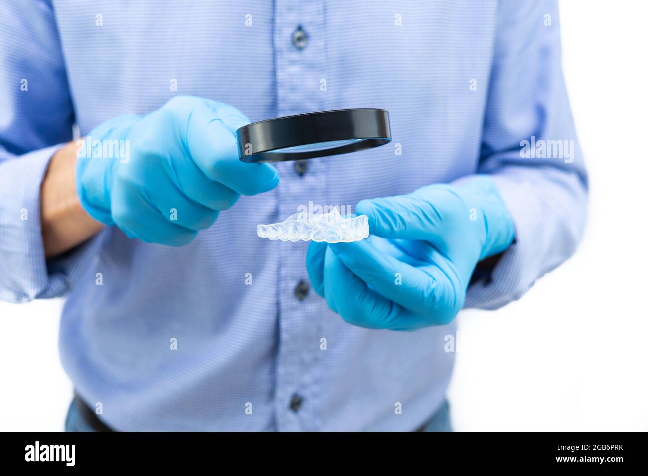 Dentist in blue gloves and shirt examining a clear dental splint with ...
