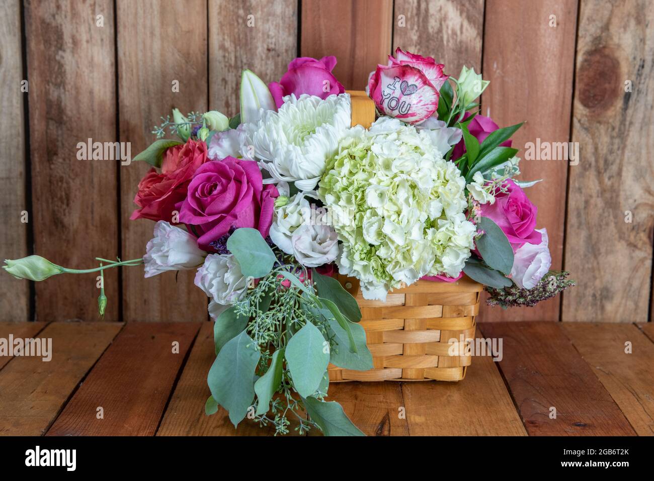 Beautiful basket bouquet of arranged roses and white flowers given as an emotional sentiment of I Love You. Stock Photo