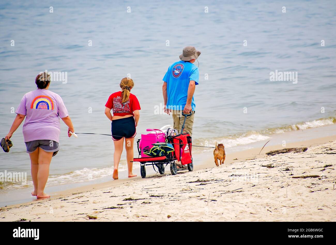 A family walks with their dog on Fort Morgan Peninsula at Mobile Point, July 31, 2021, in Gulf Shores, Alabama. Stock Photo