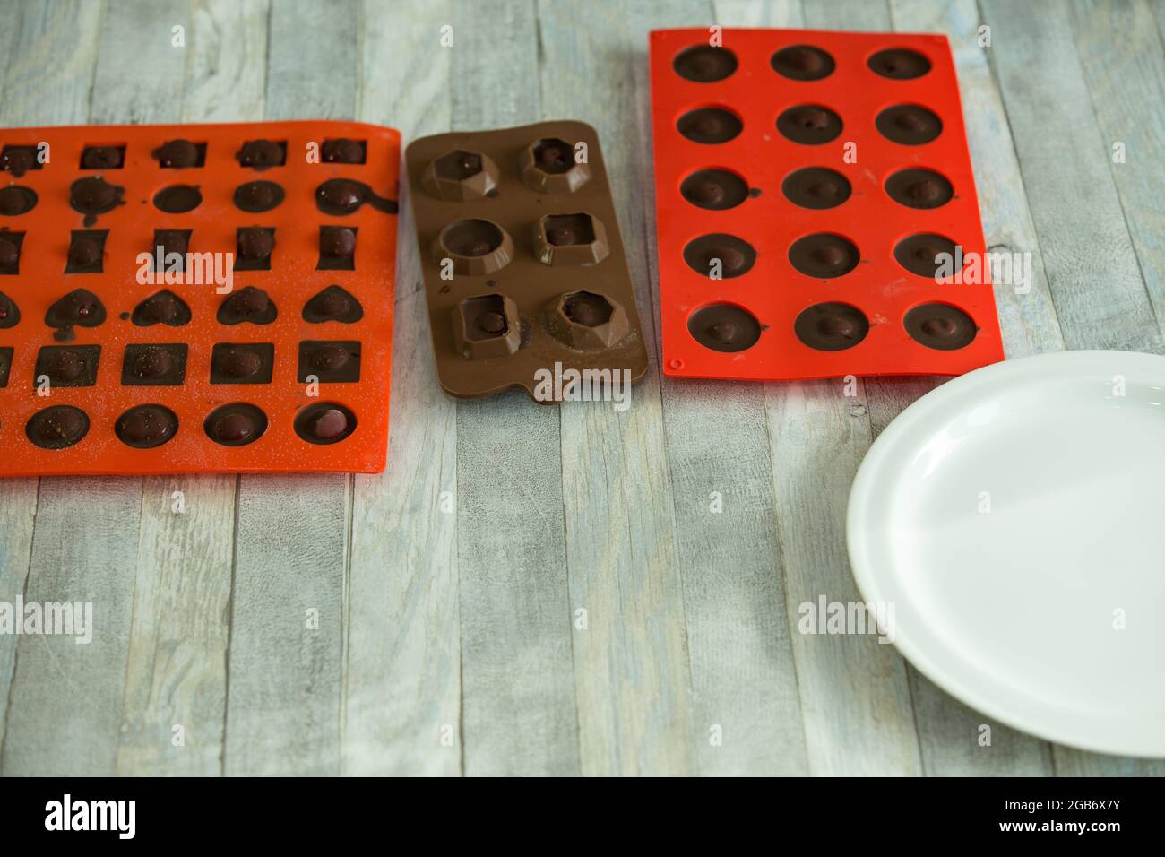 Step-by-step process of making chocolates from dark chocolate and cherries in cognac at home. Candies in silicone molds are prepared for packaging. Cu Stock Photo