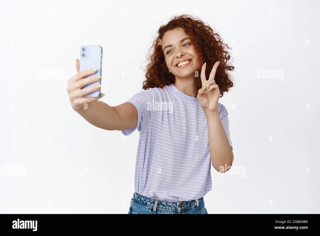 Happy beautiful girl taking selfie on smartphone with peace sign ...