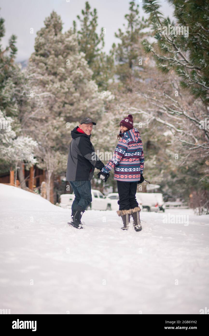 Loving couple walk outside holding hands during winter time in Big Bear, CA. Stock Photo