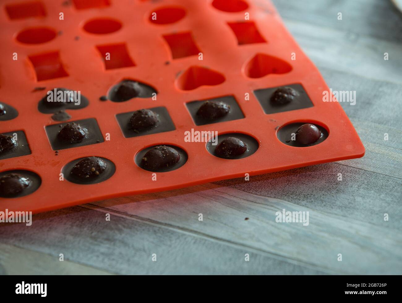 Step-by-step process of making chocolates from dark chocolate and cherries in cognac at home. Candies in silicone molds are prepared for packaging. Cu Stock Photo