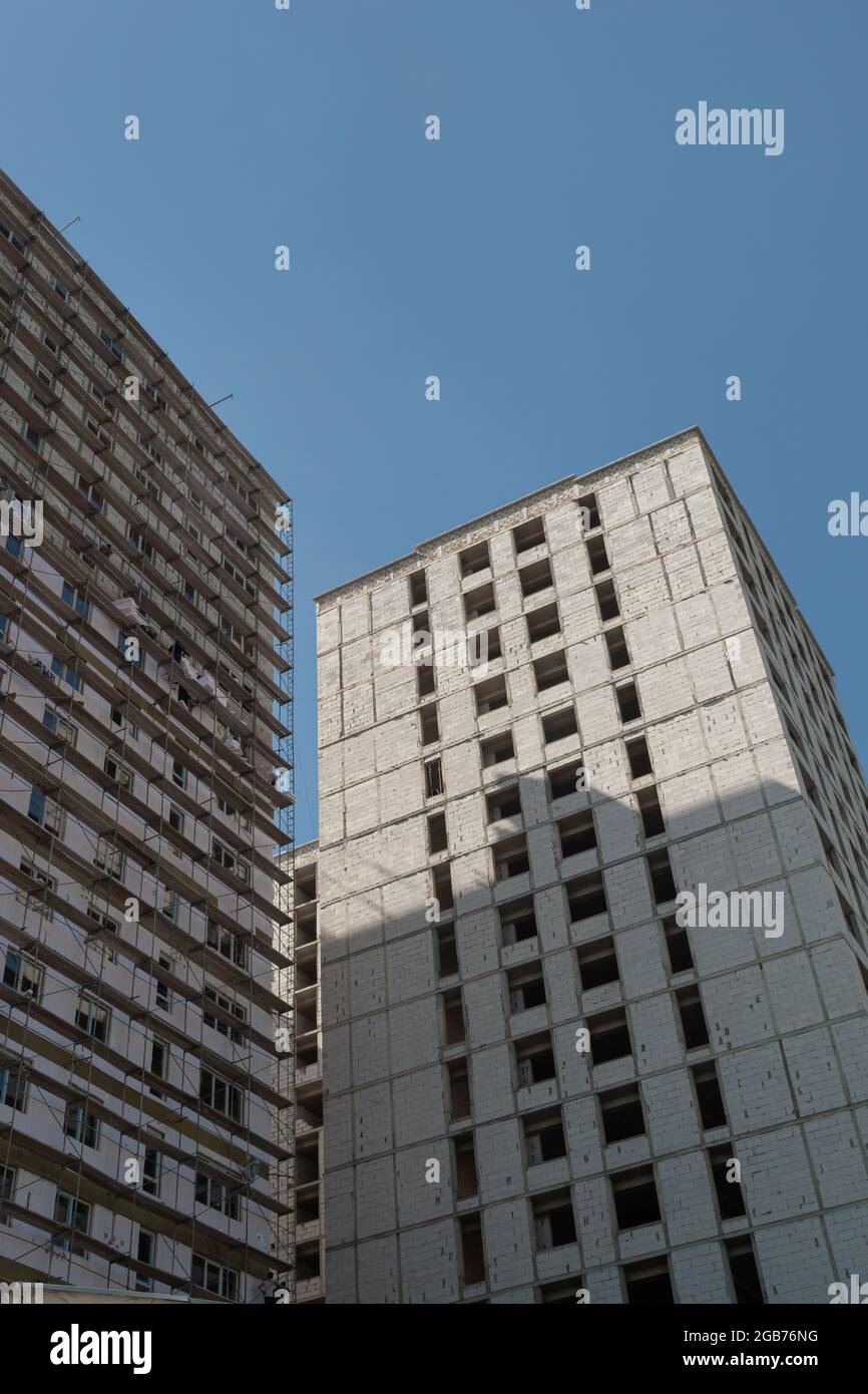 Multi-storey residential building under construction and crane on a background of blue sky Stock Photo