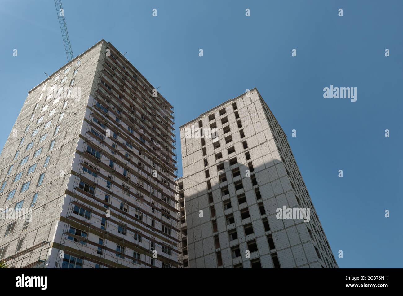 Multi-storey residential building under construction and crane on a background of blue sky Stock Photo