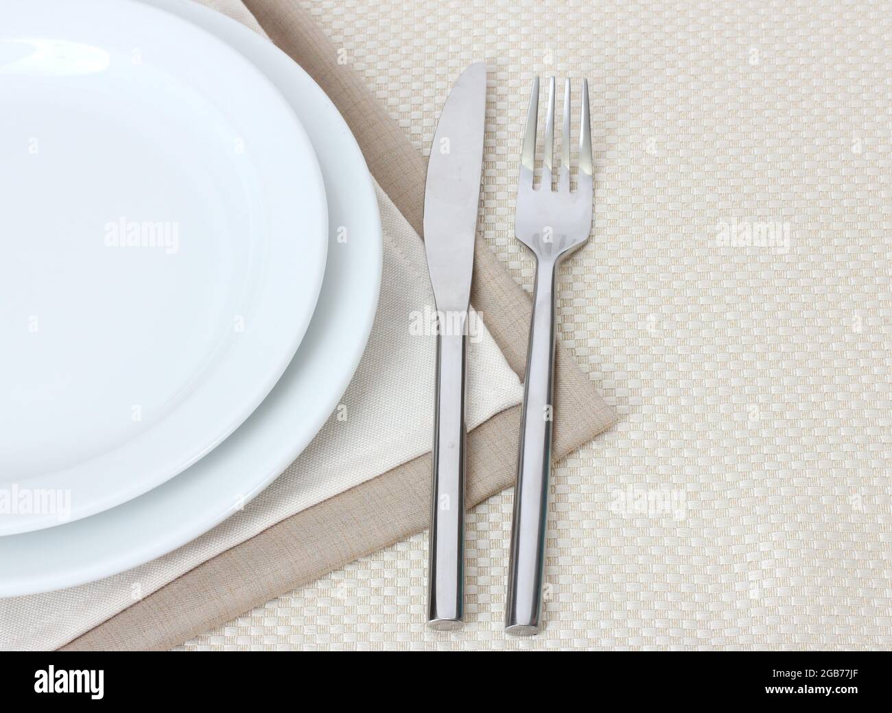 Table setting with fork, knife, plates, and napkin Stock Photo - Alamy
