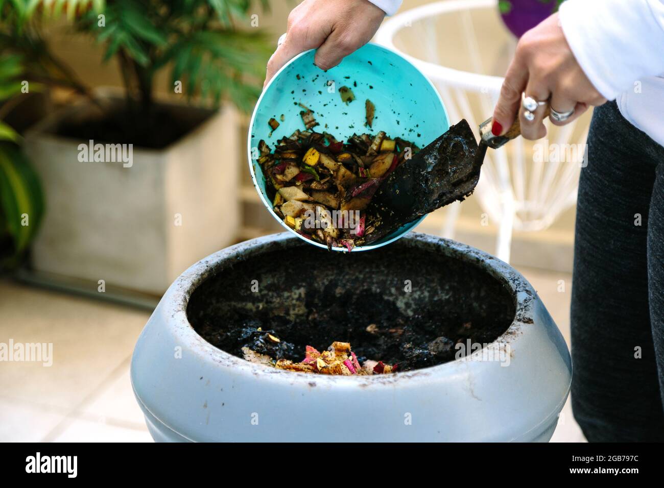 Woman doing compost in the backyard of his house. She is throwing waste ...