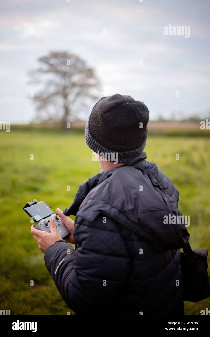 Middle aged man in outdoors clothing operating a Drone in the countryside. Stock Photo