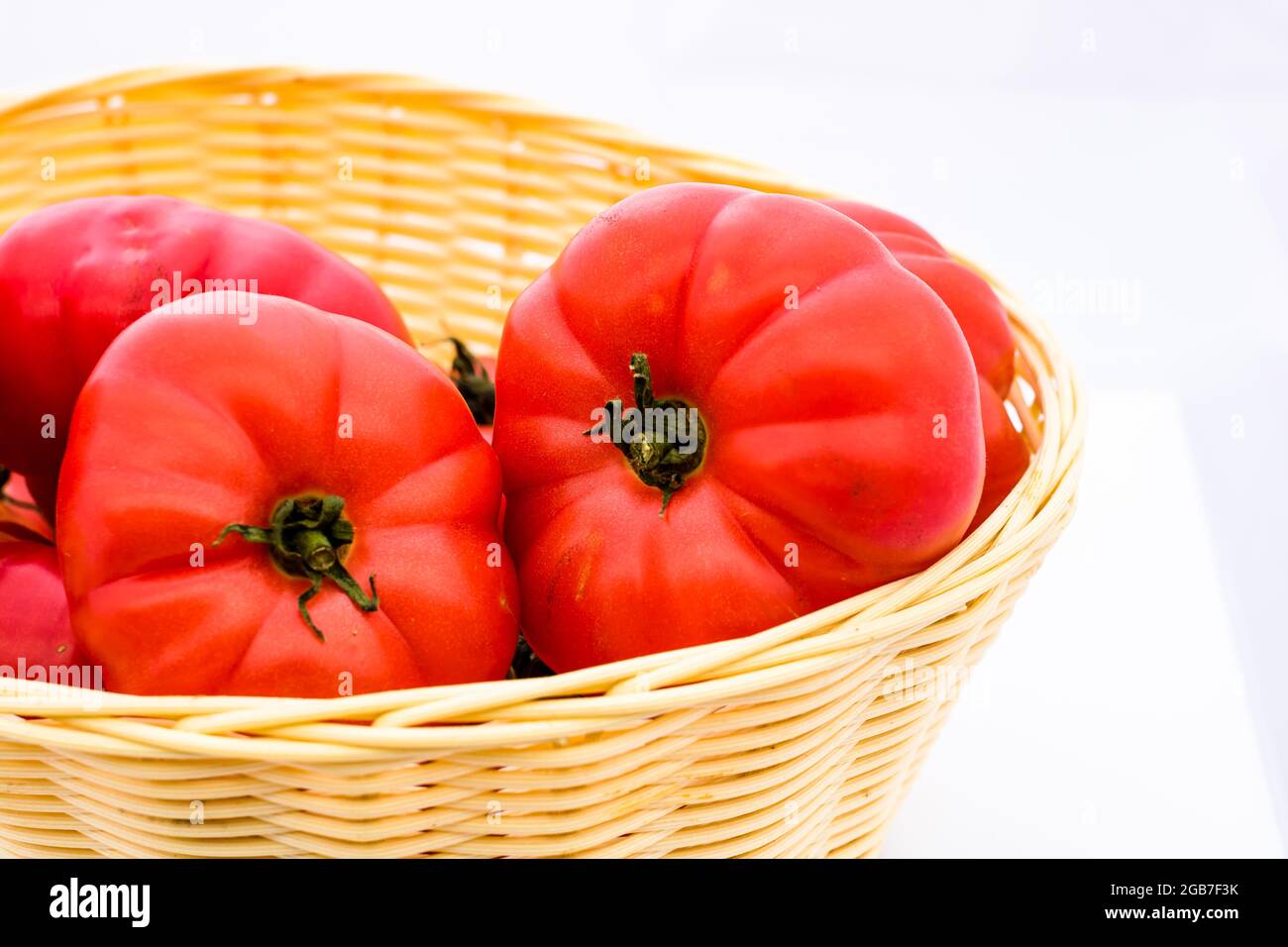 Fresh and tasty red tomatoes in wicker basket isolated Stock Photo - Alamy