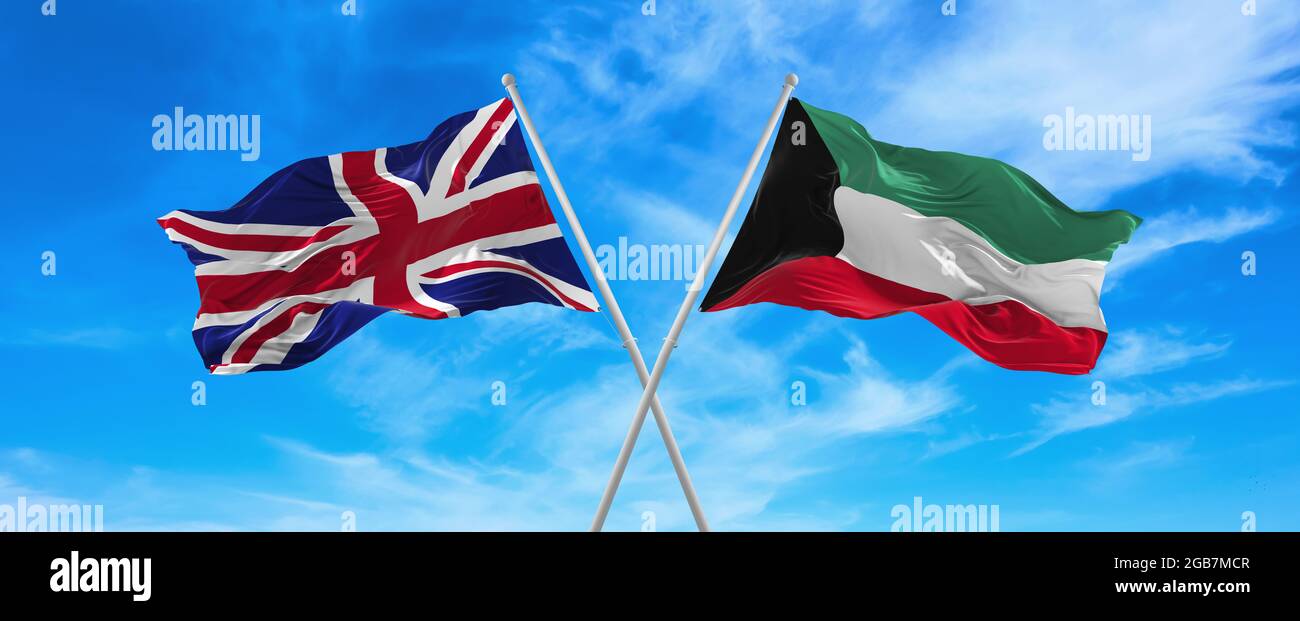 flags of great Britain and Kuwait waving in the wind on flagpoles against sky with clouds on sunny day. Symbolizing relationship, dialog between two c Stock Photo