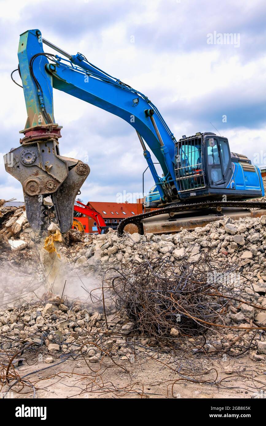 Demolition excavator separating irons and concrete on construction site - Abbruchbagger trennt Eisen und Beton auf Baustelle Stock Photo