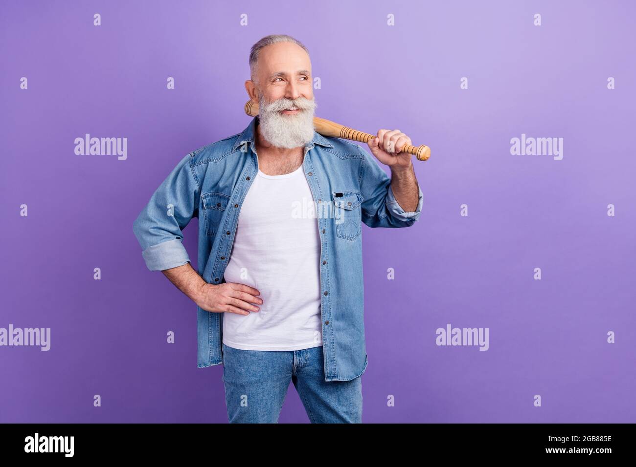 Photo of confident cute age gentleman wear jeans shirt arm waist holding bit looking empty space isolated violet color background Stock Photo