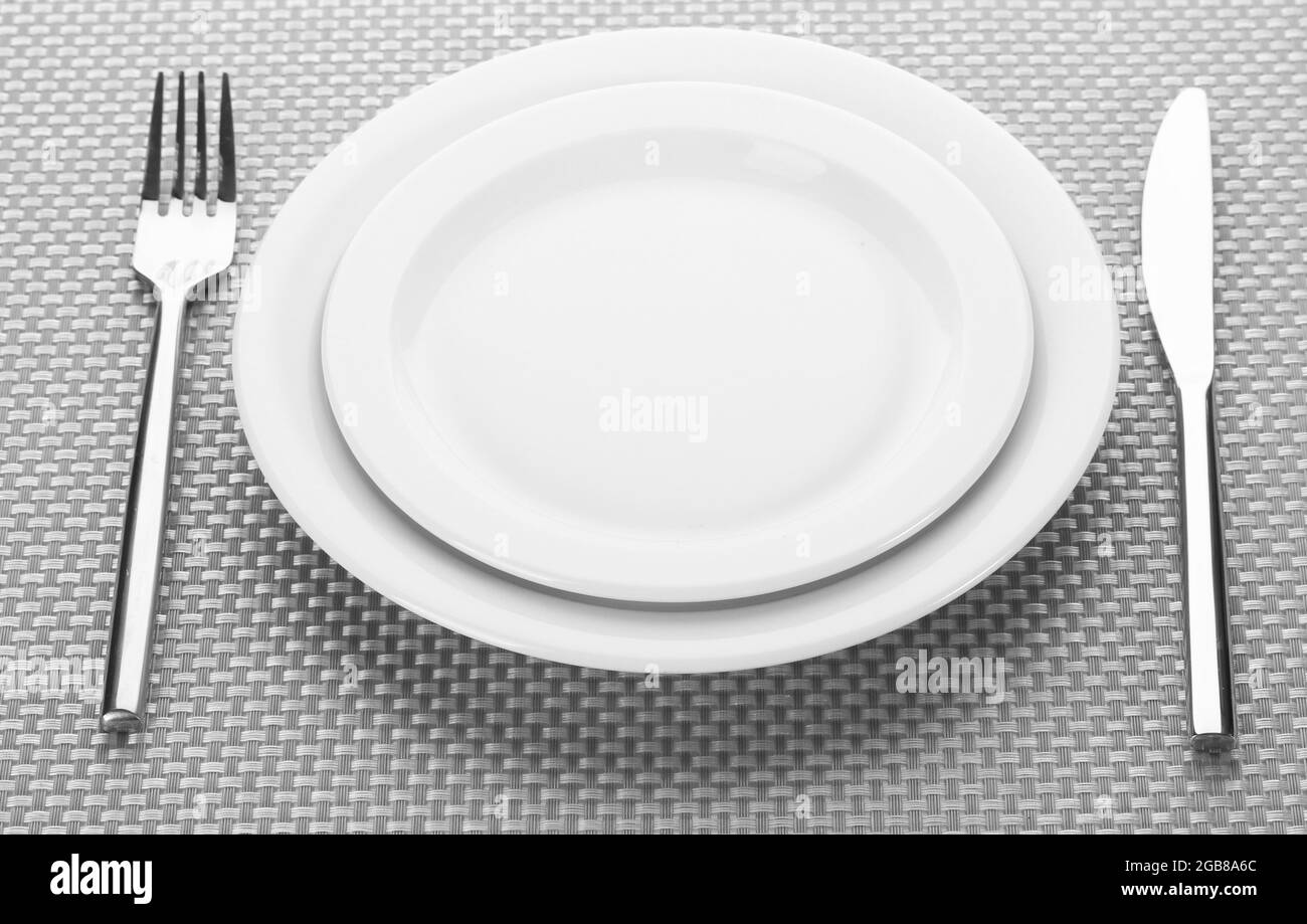 White empty plates with fork and knife on a grey tablecloth Stock Photo ...