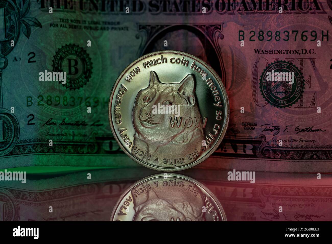 Doge cryptocurrency physical coin placed next to US dollar in the dark background and lit with green and red lights Stock Photo
